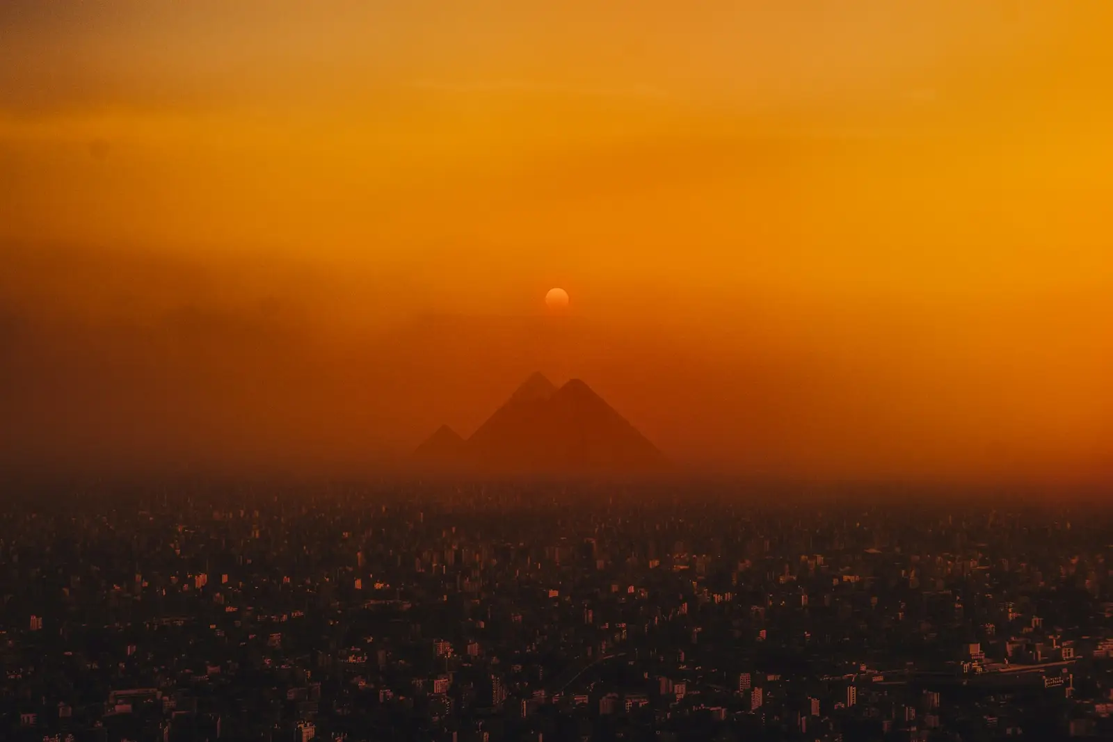 Die Pyramiden von Gizeh als Silhouette über Kairo bei Sonnenuntergang